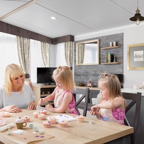A family of three in a holiday caravans for sale enjoying food and games